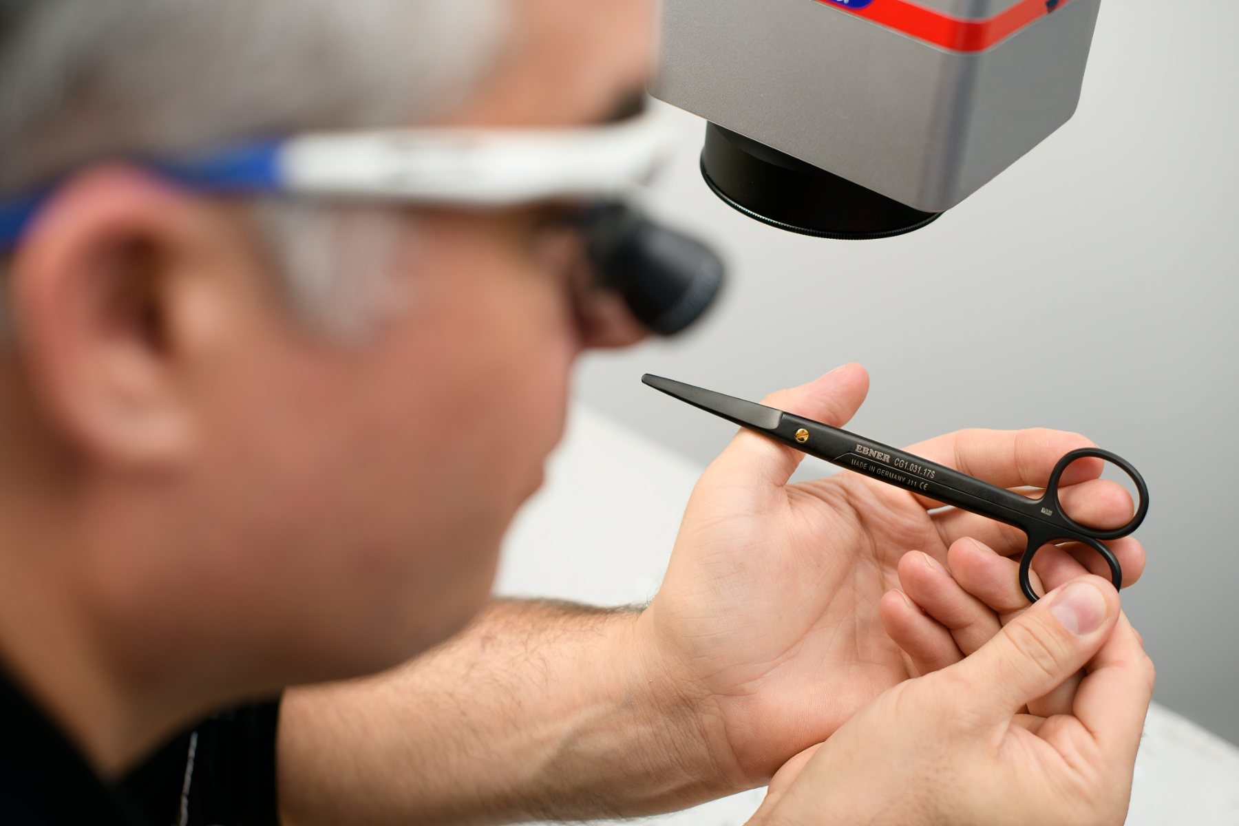 Alexander C. Ebner inspecting the EBNER Mayo scissor under a laser marking head